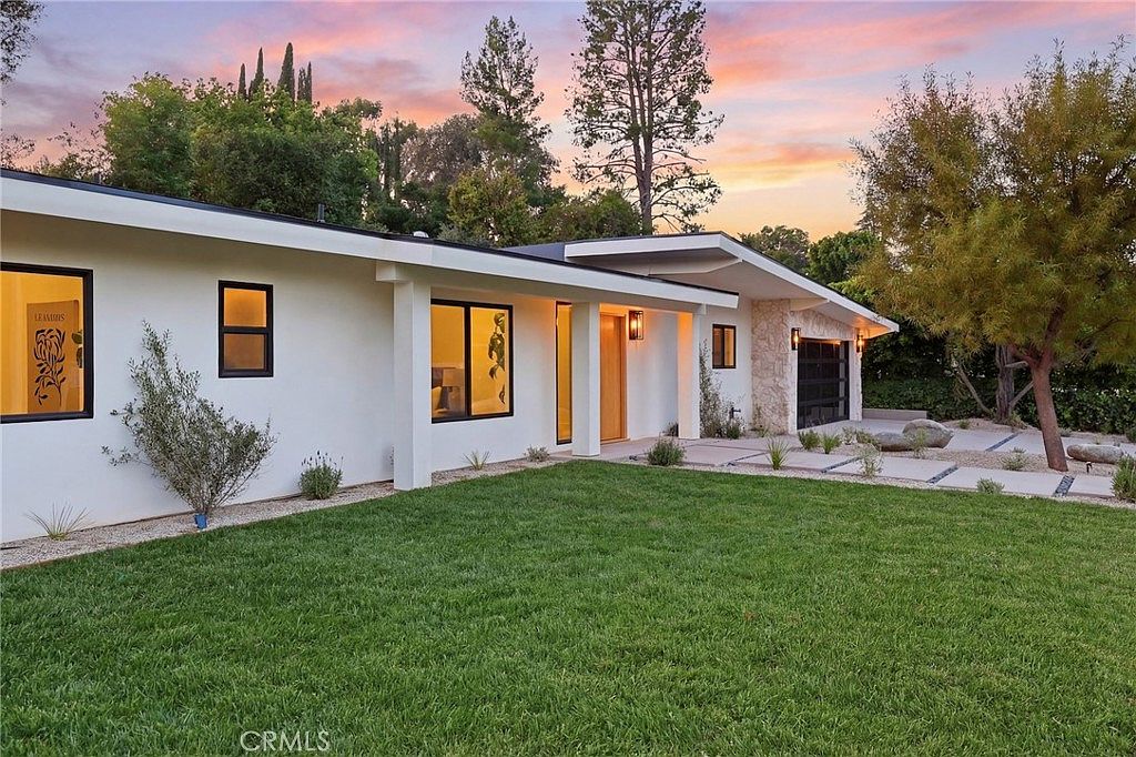 Twilight elevation with warm interior glow through tall windows and stone accent wall