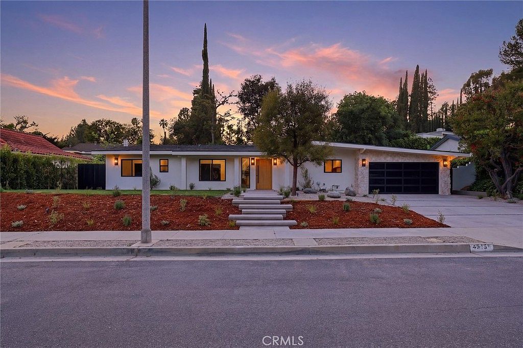 Wide street-side view at dusk showing the home's long horizontal roofline and stepped entry