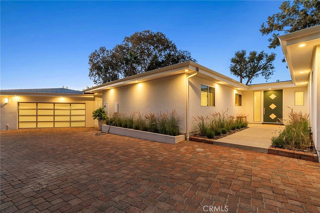 Rear paver motor court with garage and softly lit recessed entry door